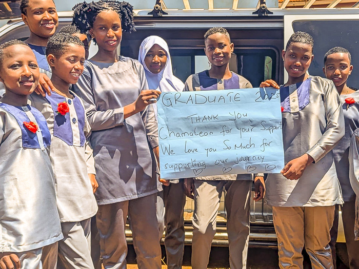 Kinder von Mwema halten ein Schild "Graduate 2025, thank you Chamäleon for your support. We love you so much for supporting our journey"